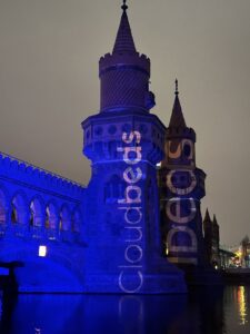 Photograph of the Oberbaum Bridge lit up blue with IDeaS and Cloudbeds logos projected upon it. 