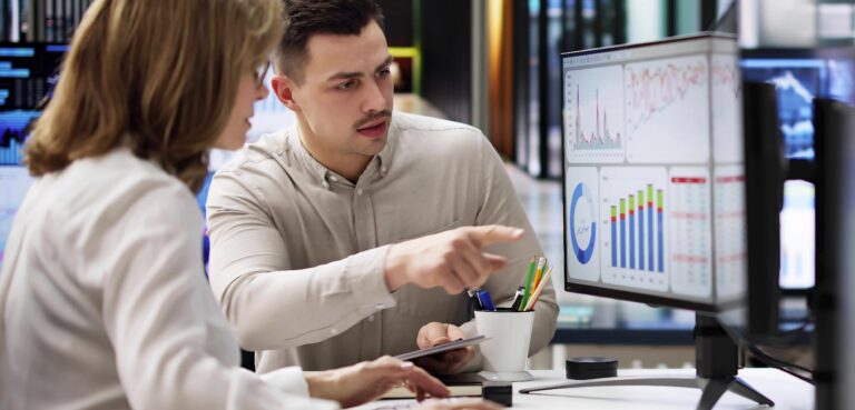 Employees gather around work station to discuss data report.