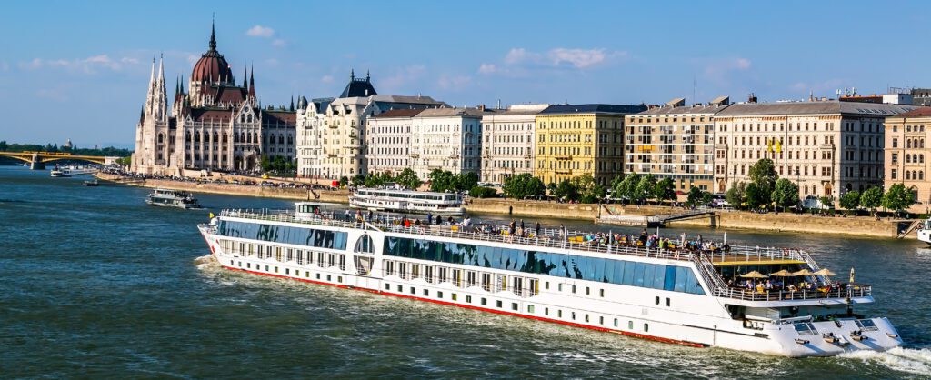 A luxury river boat, sails past the inpressive Hungarian House of Parliament on the Danube River.