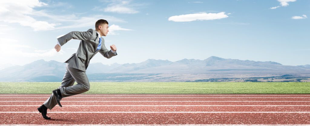 Photograph of a man in a suit in a full sprint running on a track.